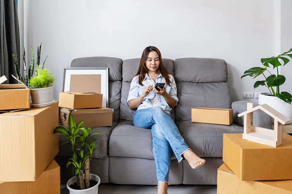 A woman sitting on her couch, surrounded with boxes after a move