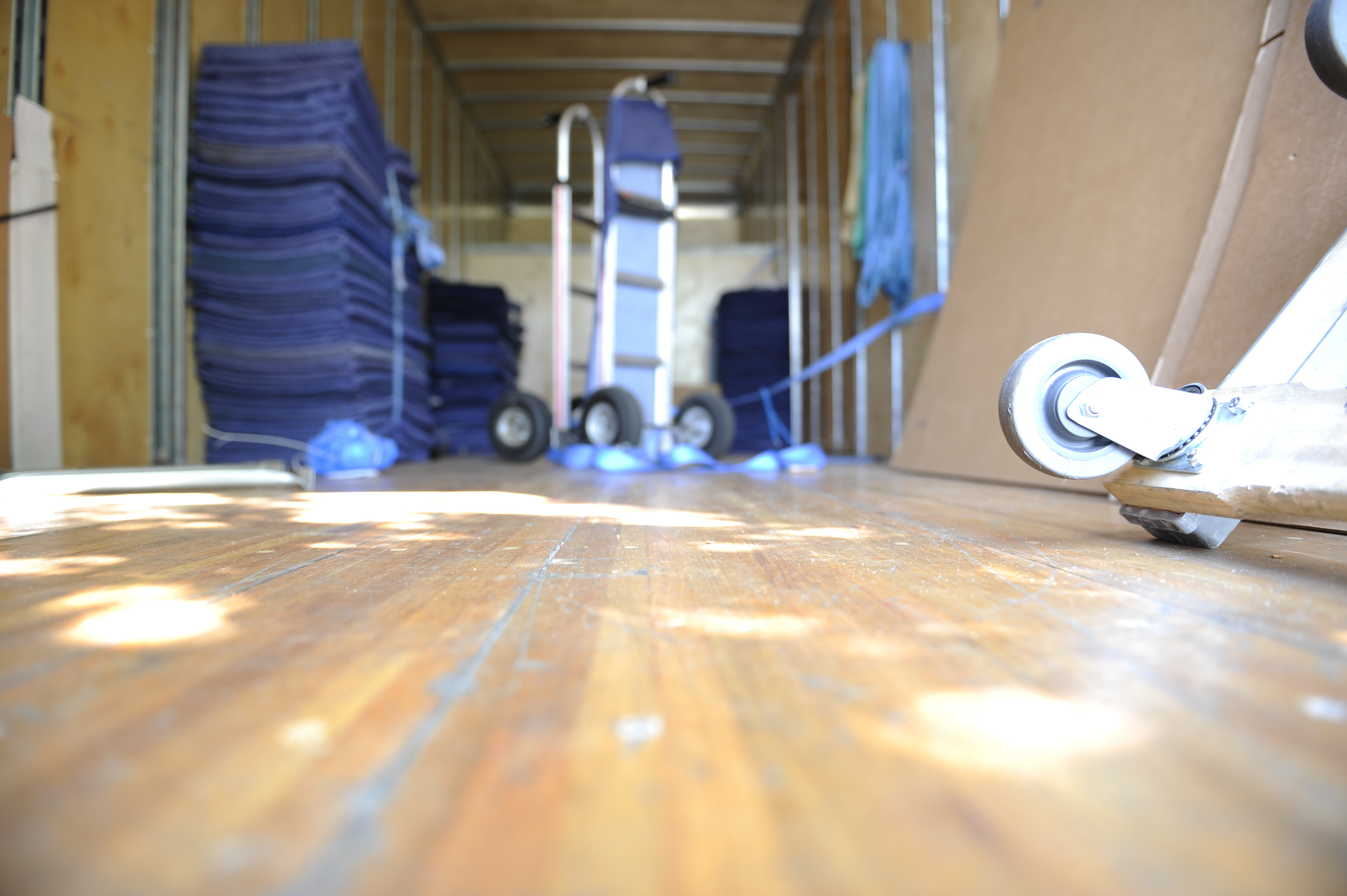 Interior of a box truck, filled with moving blankets and dollies