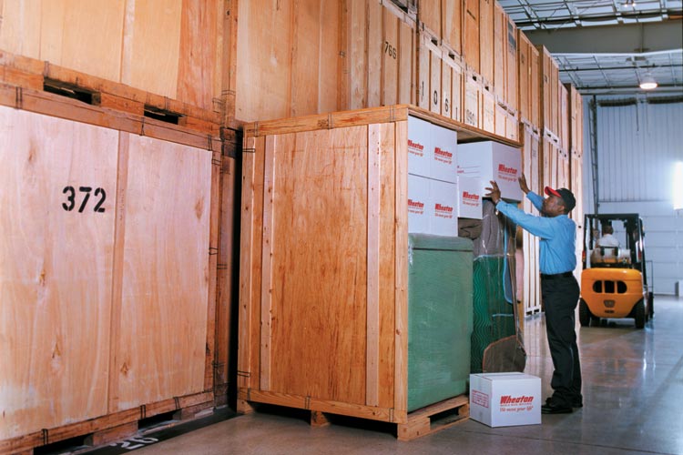 A worker in a storage unit stacking up boxes
